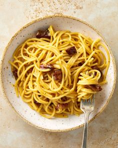 a white bowl filled with spaghetti and bacon