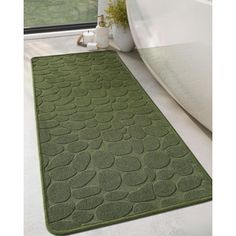 a bathroom rug that is on the floor in front of a bathtub and window