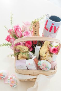 a basket filled with lots of different items on top of a white table next to pink roses