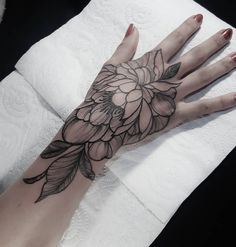 a woman's hand with a flower tattoo on it