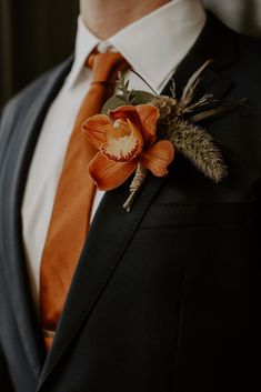 a man in a suit and tie with an orange boutonniere on his lapel