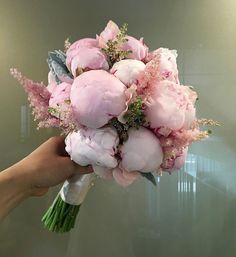 a bouquet of pink flowers being held by a person's hand in front of a mirror