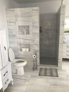 a bathroom with white and gray tile walls, flooring and toilet in the corner