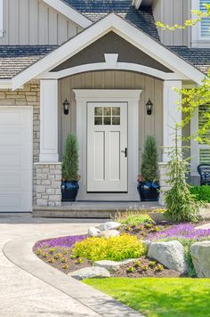 a white front door on a house with flowers in the foreground and landscaping around it