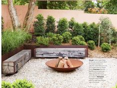 an outdoor fire pit in the middle of a gravel area with trees and bushes behind it