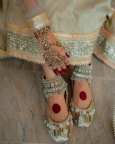 a woman's feet wearing gold and white shoes with red polka dots on them