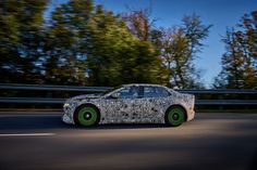 the car is driving down the road with trees in the backgrouds behind it