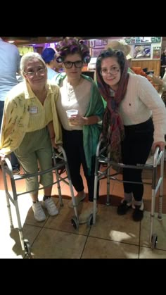 three older women standing next to each other with walkers on the floor in front of them