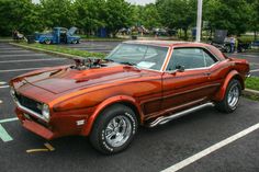 an orange muscle car parked in a parking lot