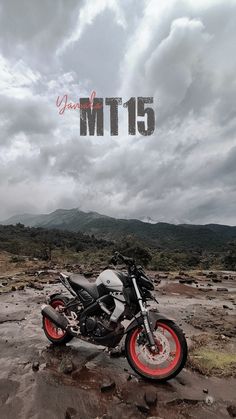 a motorcycle parked on top of a dirt field under a cloudy sky with the words mt16 above it