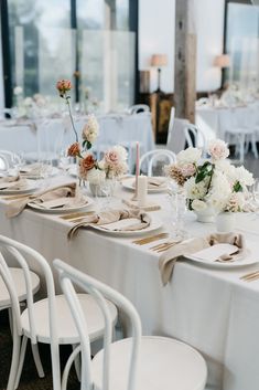 the table is set with white linens and flowers