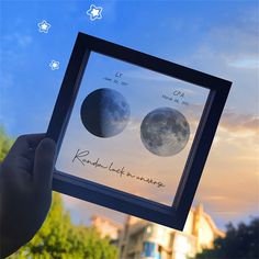 a person holding up a framed photo with two phases of the moon in front of them