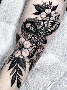 a black and white tattoo on the arm of a woman with flowers in her hair