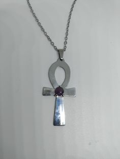 Egyptian Ankh, Cross of Life Pendant, aluminium and natural purple amethyst 

 This handcrafted pendant in the shape of an Ankh cross is made of hand-sawn aluminium, with a natural amethyst stone
 It is handmade, unique and made in France.
 Sold with or without a silver color stainless steel chain (option)

 This mythological cross will make a perfect gift for a lover of handcrafted jewelry and Egyptian mythology.

 Materials: aluminium, amethyst, stainless steel.
 Like any jewel, take care of i Silver Ankh Cross Necklace In Spiritual Style, Silver Ankh Cross Necklace Spiritual Style, Ankh Shaped Metal Necklace As Gift, Luxury Symbolic Ankh Necklace, Silver Ankh Cross Spiritual Necklace, Nickel-free Ankh Necklace As Gift, Silver Ankh Amulet Necklace, Purple Amethyst Cross Necklace, Elegant Ankh-shaped Hallmarked Necklace