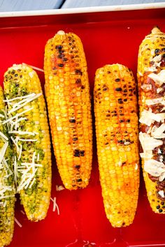 corn on the cob with parmesan cheese and other toppings in a red tray