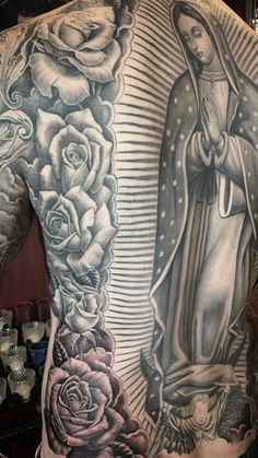 the back of a man with tattoos and roses on his chest, in front of a mirror