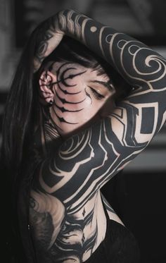 a woman with black and white tattoos on her body is holding her hands behind her head