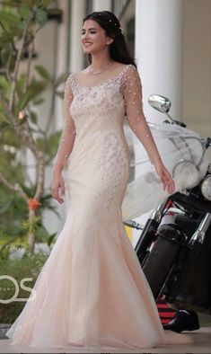 a woman standing next to a motorcycle wearing a wedding dress with beading on it