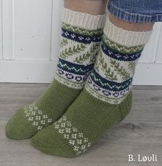 the legs of a woman wearing green socks with white and blue knitted designs on them