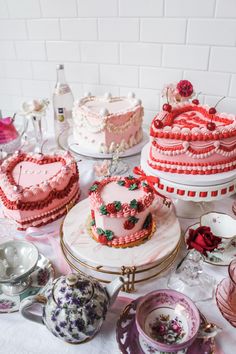 a table topped with lots of cakes covered in frosting and pink icing on top of plates