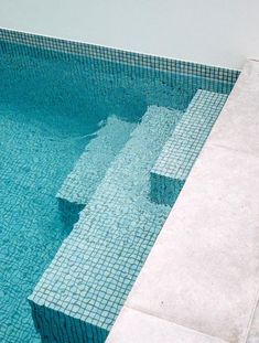 an empty swimming pool with steps leading up to the water's edge and tiled floor