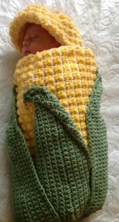 a newborn baby wrapped in a green and yellow knitted blanket with a hat on it's head