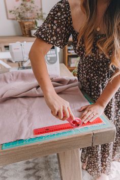 a woman is cutting fabric on a table