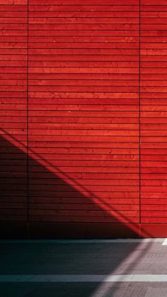 a man riding a skateboard down a street next to a red wall