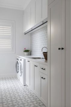 a washer and dryer in a white laundry room with tile flooring on the walls