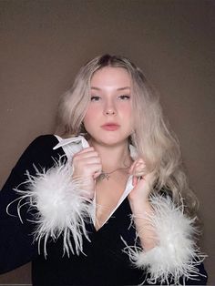 a woman with blonde hair and white feathers on her neck is posing for the camera