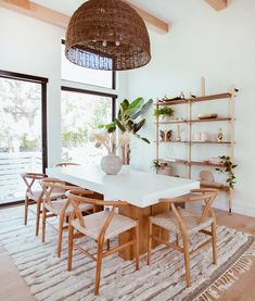 a dining room table and chairs in front of a large window with plants on it