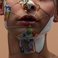 a woman's face is covered in gold wire and has flowers on her neck