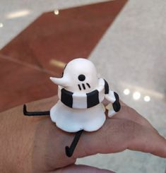 a hand holding a small white and black figurine