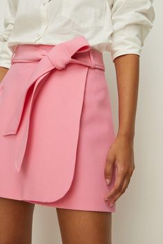 Expertly crafted in a premium fabric, this mini skirt shows off a flattering wrap fit to create a feminine silhouette. Complete with a matching belt to further cinch in silhouettes, pair with everything from simple tank tops to floral blouses. Model wears a size 10.