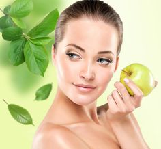 a woman holding an apple in front of her face and green leaves around her neck