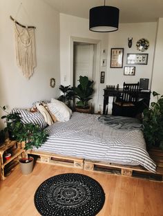 a bedroom with a bed made out of wooden pallets and plants on the floor