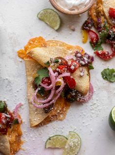 some food is laying out on a white surface with limes and other things around it