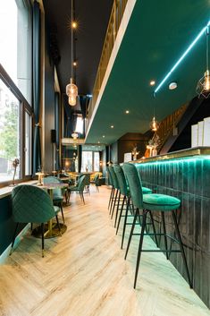 the interior of a restaurant with green velvet chairs and bar stools in front of large windows