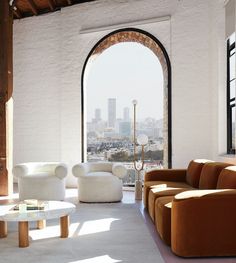 a living room filled with furniture and a large window next to a white brick wall