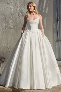 a woman in a white wedding dress standing on steps with her hands behind her back