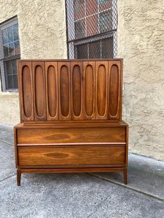 a wooden bench sitting on the side of a road next to a building with a window