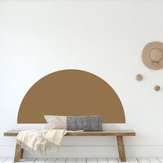 a wooden bench sitting in front of a white wall with a brown circle on it