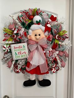 a christmas wreath on the front door with an elf and candy canes decoration around it