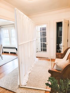 a living room with a white drape on the wall and wooden floors in front of it