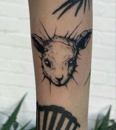 a tattoo on the leg of a person with a goat head and cross in it