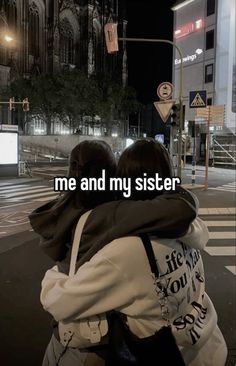 two people hugging each other in the middle of a street at night with words written on them