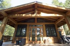 a large wooden building with glass doors and windows on the front porch, surrounded by trees