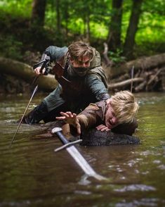 two people are in the water with swords