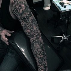 a man sitting in a chair with a tattoo on his arm