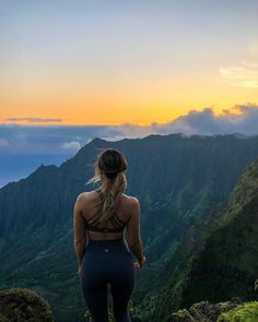 a woman standing on top of a mountain looking at the sky and mountains in the distance